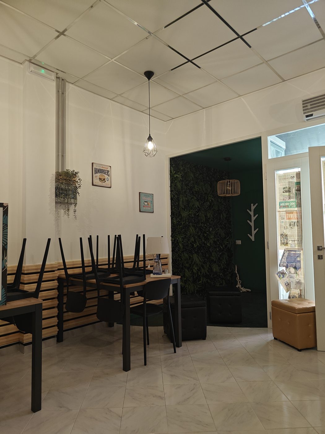 La sala di Crøcco: tavoli neri, listoni di legno e parete verde